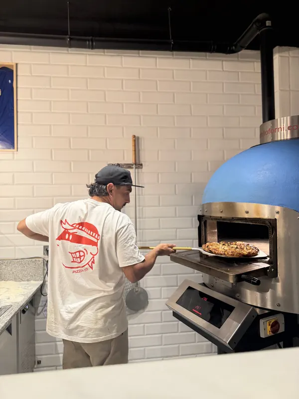 Pizzero metiendo una pizza en el horno de Malandra Balmes, Palma