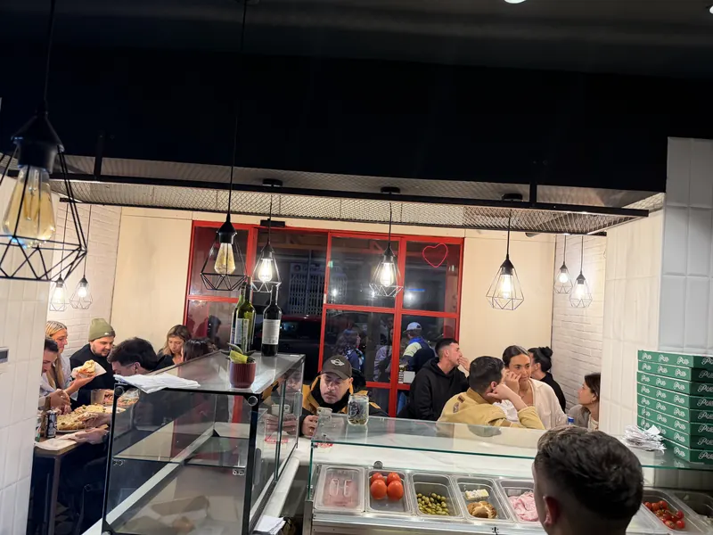Mostrador de Malandra Balmes con clientes esperando su pizza para llevar en Palma