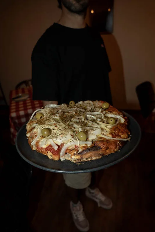 Pizza argentina con cebolla y olivas verdes recién salida del horno en Malandra Santa Catalina, Palma