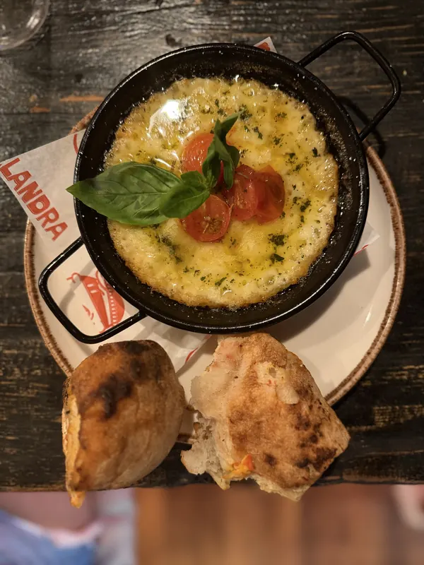 Provoleta con tomate cherry confitado y albahaca, con pan de pizza, en Malandra Santa Catalina